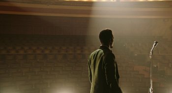 Movie still from “Detroit” (2017), directed by Kathryn Bigelow – A man standing in front of an audience in front of a stage; Extreme Wide shot, Low angle