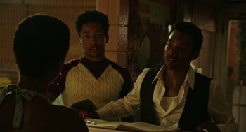 Movie still from “Detroit” (2017), directed by Kathryn Bigelow – A group of people sitting at a table; Medium shot, Over the shoulder angle