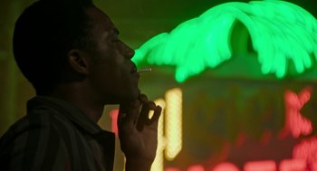 Movie still from “Detroit” (2017), directed by Kathryn Bigelow – A man smoking a cigarette in front of a neon sign; Close Up shot, Low angle