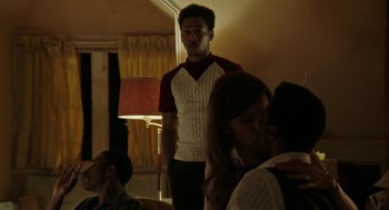 Movie still from “Detroit” (2017), directed by Kathryn Bigelow – A group of people in a room with a man standing in front of a woman; Medium shot, Over the shoulder angle