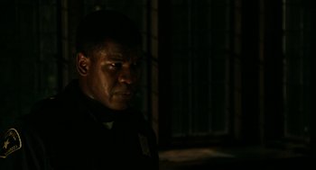 Movie still from “Detroit” (2017), directed by Kathryn Bigelow – A man in a dark room looking at the camera; Close Up shot, Low angle
