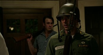 Movie still from “Detroit” (2017), directed by Kathryn Bigelow – A man in a military uniform holding a gun; Medium shot, Over the shoulder angle