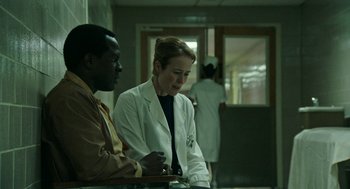Movie still from “Detroit” (2017), directed by Kathryn Bigelow – Two people in lab coats sitting at a table; Medium shot, Over the shoulder angle