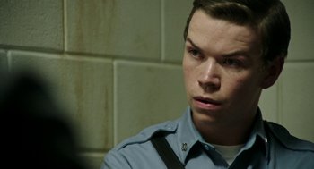 Movie still from “Detroit” (2017), directed by Kathryn Bigelow – A man in a police uniform looking to his left; Close Up shot, Over the shoulder angle