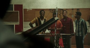 Movie still from “Detroit” (2017), directed by Kathryn Bigelow – A man standing next to two women in a recording studio; Medium shot, High angle