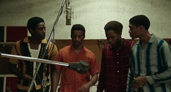 Movie still from “Detroit” (2017), directed by Kathryn Bigelow – A group of men standing in front of a microphone in a room; Medium shot, High angle