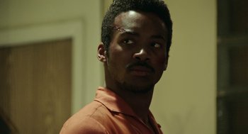 Movie still from “Detroit” (2017), directed by Kathryn Bigelow – A person wearing a orange shirt; Close Up shot, Low angle