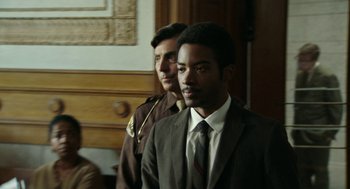 Movie still from “Detroit” (2017), directed by Kathryn Bigelow – A man in a suit and tie standing next to another man in a suit and tie; Close Up shot, Over the shoulder angle