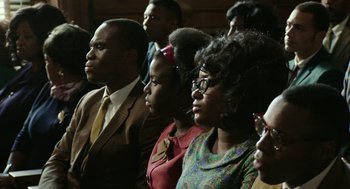 Movie still from “Detroit” (2017), directed by Kathryn Bigelow – A group of people sitting in a room together; Medium shot, High angle