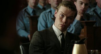 Movie still from “Detroit” (2017), directed by Kathryn Bigelow – A man in a suit and tie in front of a group of people; Close Up shot, Over the shoulder angle