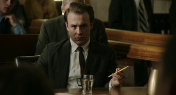 Movie still from “Detroit” (2017), directed by Kathryn Bigelow – A man sitting at a table holding a pencil; Medium shot, Over the shoulder angle