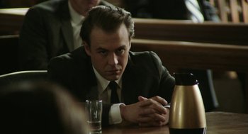 Movie still from “Detroit” (2017), directed by Kathryn Bigelow – A man sitting at a table with a drink in front of him; Close Up shot, Low angle