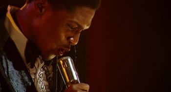 Movie still from “Detroit” (2017), directed by Kathryn Bigelow – A person holding a microphone up to their mouth; Close Up shot, Low angle