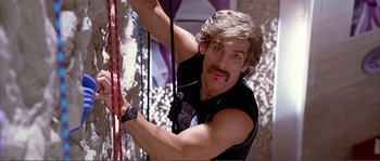 Movie still from “Dodgeball: A True Underdog Story” (2004), directed by Rawson Marshall Thurber – A man with a mustache is climbing a rock wall; Medium shot, Low angle