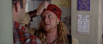 Movie still from “Dodgeball: A True Underdog Story” (2004), directed by Rawson Marshall Thurber – A man with long blonde hair wearing a red bandana; Close Up shot, Over the shoulder angle