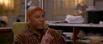 Movie still from “Dodgeball: A True Underdog Story” (2004), directed by Rawson Marshall Thurber – A bald man wearing an orange and brown shirt; Close Up shot, Over the shoulder angle