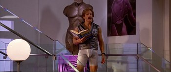 Movie still from “Dodgeball: A True Underdog Story” (2004), directed by Rawson Marshall Thurber – A man in white underwear holding an open book; Medium shot, Low angle