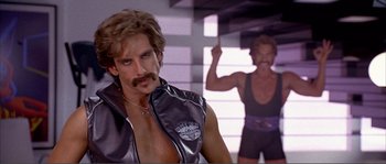 Movie still from “Dodgeball: A True Underdog Story” (2004), directed by Rawson Marshall Thurber – A man with a mustache and a beard is standing next to another man with no shirt; Close Up shot, Low angle