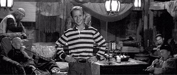 Movie still from “Dodgeball: A True Underdog Story” (2004), directed by Rawson Marshall Thurber – A young man standing in front of a table; Medium shot, Low angle