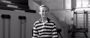 Movie still from “Dodgeball: A True Underdog Story” (2004), directed by Rawson Marshall Thurber – Black and white photograph of a young boy wearing a striped shirt; Medium shot, High angle