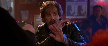 Movie still from “Dodgeball: A True Underdog Story” (2004), directed by Rawson Marshall Thurber – A man with long brown hair and a beard is making a funny face while holding his hands up; Close Up shot, Over the shoulder angle