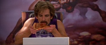 Movie still from “Dodgeball: A True Underdog Story” (2004), directed by Rawson Marshall Thurber – A man sitting in front of a computer eating a slice of pizza; Medium shot, High angle