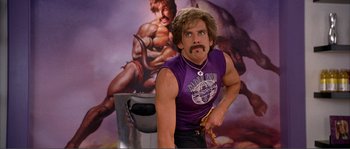 Movie still from “Dodgeball: A True Underdog Story” (2004), directed by Rawson Marshall Thurber – A man in a purple tank top holding a knife; Medium shot, Low angle