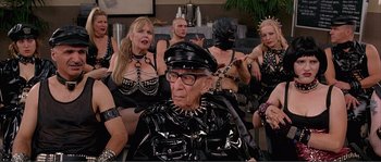 Movie still from “Dodgeball: A True Underdog Story” (2004), directed by Rawson Marshall Thurber – A group of men and women in fetishes sitting in a room; Medium shot, Over the shoulder angle