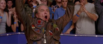 Movie still from “Dodgeball: A True Underdog Story” (2004), directed by Rawson Marshall Thurber – An older man in a brown leather jacket is yawning in front of a group of people; Close Up shot, Low angle