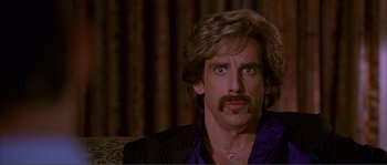 Movie still from “Dodgeball: A True Underdog Story” (2004), directed by Rawson Marshall Thurber – A man that is wearing a purple shirt and a mustache; Close Up shot, Over the shoulder angle