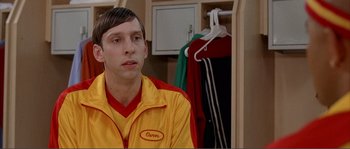 Movie still from “Dodgeball: A True Underdog Story” (2004), directed by Rawson Marshall Thurber – A man in a yellow and red jacket sitting in front of a closet; Close Up shot, Low angle