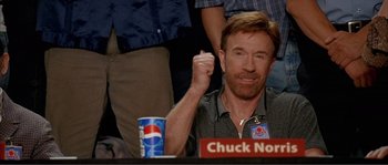 Movie still from “Dodgeball: A True Underdog Story” (2004), directed by Rawson Marshall Thurber – A man sitting in front of a table with a cup of soda; Medium shot, Low angle