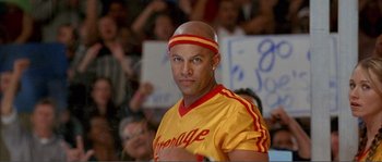 Movie still from “Dodgeball: A True Underdog Story” (2004), directed by Rawson Marshall Thurber – A bald man in a yellow and red shirt is in front of a group of people; Close Up shot, Low angle