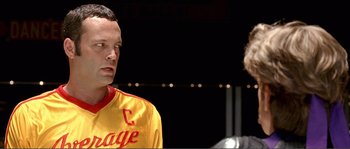 Movie still from “Dodgeball: A True Underdog Story” (2004), directed by Rawson Marshall Thurber – A man in a yellow and red shirt standing next to another man; Close Up shot, Over the shoulder angle