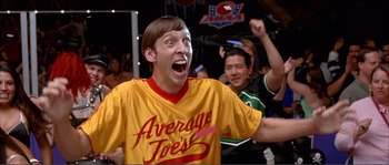 Movie still from “Dodgeball: A True Underdog Story” (2004), directed by Rawson Marshall Thurber – A man in an average joe's shirt is cheering; Medium shot, Low angle