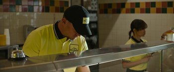 Movie still from “Dog” (2022), directed by Reid Carolin – A man wearing a yellow shirt and a black hat; Medium shot, Low angle