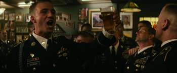 Movie still from “Dog” (2022), directed by Reid Carolin – A group of men in uniform holding up a glass of beer; Medium shot, Low angle