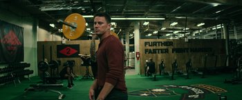 Movie still from “Dog” (2022), directed by Reid Carolin – A man is standing in a gym holding a barbell; Medium shot, Low angle