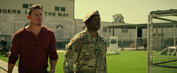 Movie still from “Dog” (2022), directed by Reid Carolin – A man in military fatigues is standing in the grass; Medium shot, Over the shoulder angle