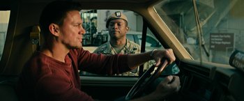 Movie still from “Dog” (2022), directed by Reid Carolin – A man driving a car while another man in a uniform looks on; Medium shot, Over the shoulder angle