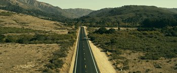 Movie still from “Dog” (2022), directed by Reid Carolin – An aerial view of a road with a car driving down it; Extreme Wide shot, High angle