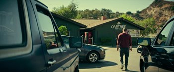 Movie still from “Dog” (2022), directed by Reid Carolin – A man walking down a street next to a car; Wide shot, Over the shoulder angle