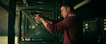 Movie still from “Dog” (2022), directed by Reid Carolin – A man is holding a gun in a room; Medium shot, Low angle