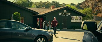 Movie still from “Dog” (2022), directed by Reid Carolin – A group of people walking down a street near a building; Wide shot, Low angle