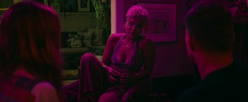 Movie still from “Dog” (2022), directed by Reid Carolin – A woman sitting on a chair in a room with purple lighting; Medium shot, High angle