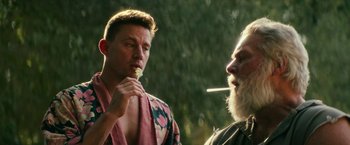Movie still from “Dog” (2022), directed by Reid Carolin – A man in a robe is smoking a cigarette while another man is brushing his teeth; Close Up shot, Over the shoulder angle