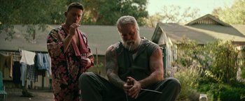 Movie still from “Dog” (2022), directed by Reid Carolin – An older man smoking a cigarette while sitting next to a woman; Medium shot, Low angle