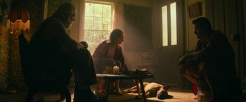 Movie still from “Dog” (2022), directed by Reid Carolin – An old woman sitting at a table in a room with a dog; Wide shot, High angle