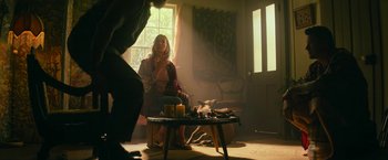 Movie still from “Dog” (2022), directed by Reid Carolin – A woman sitting on a chair in a room; Wide shot, Low angle