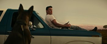 Movie still from “Dog” (2022), directed by Reid Carolin – A man sitting in the back of an airplane holding a cell phone; Medium shot, Low angle